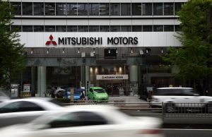 Traffic moves past Mitsubishi Motors Corp. Mirage vehicles displayed outside the company's headquarters in Tokyo, Japan, on Wednesday, April 24, 2013. Mitsubishi Motors plans to increase production at the company's Mizushima plant in western Japan, according to a statement. Photographer: Tomohiro Ohsumi/Bloomberg